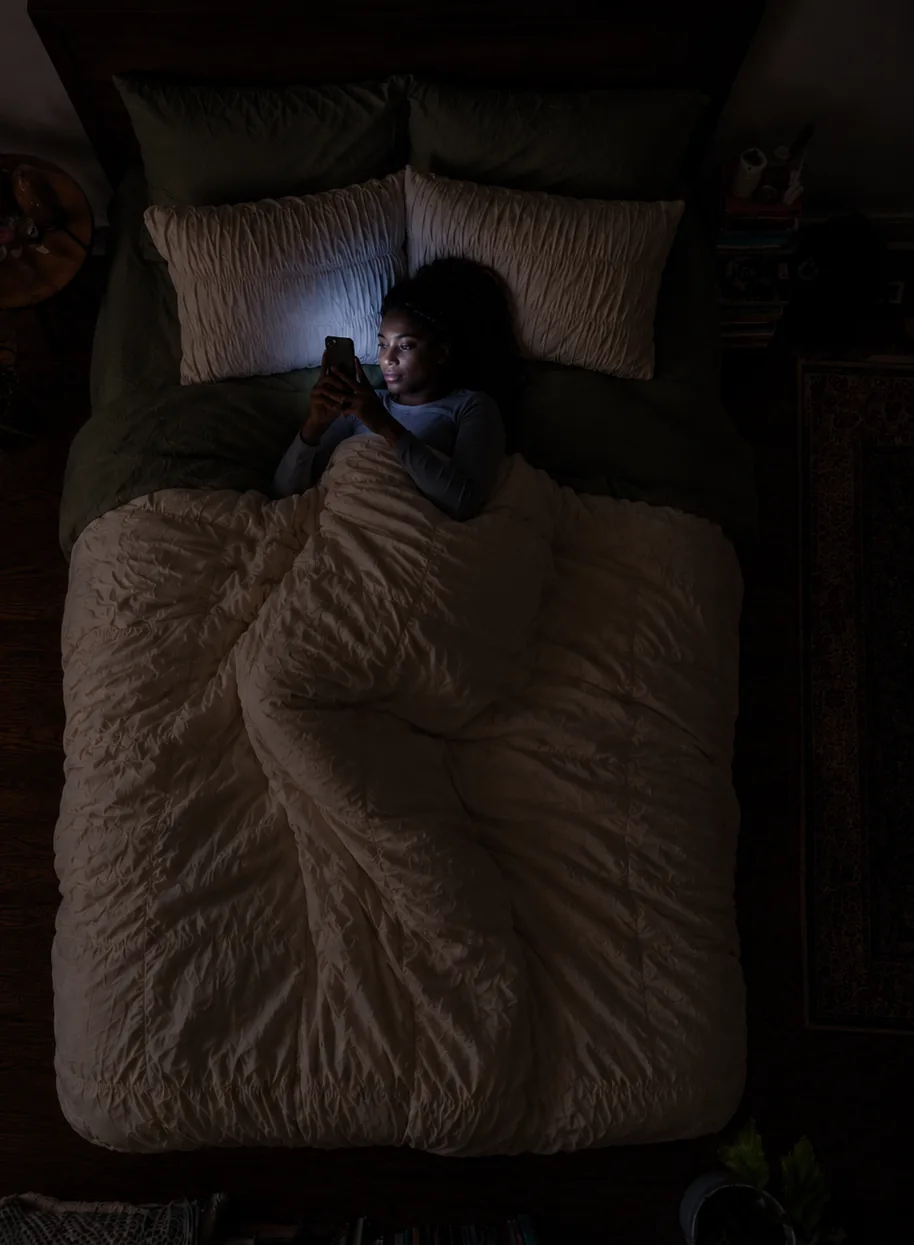 Scrolling in bed at night, face lit by the phone